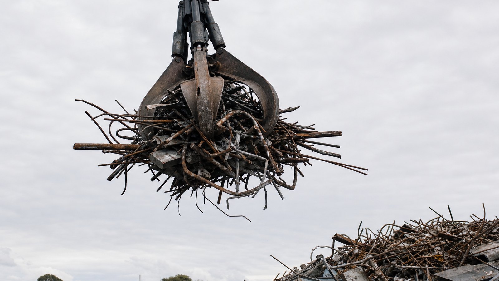 A grab claw lifting mixed steel scrap in a yard